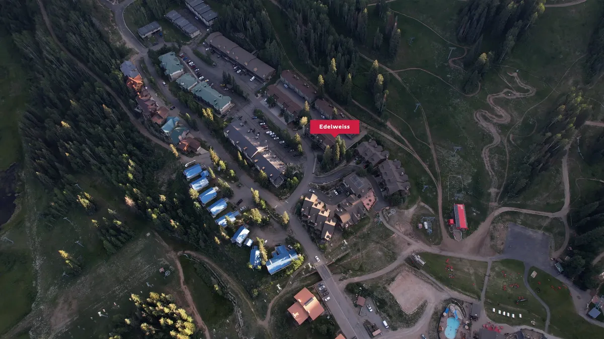 The Edelweiss building is nestled amid verdant greenery, with walking paths leading directly into the San Juan National Forest. The setting is serene, with nature at the doorstep and forested trails beckoning for exploration.