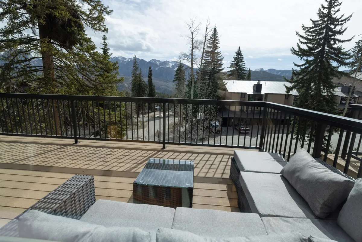 A deck seating area with a coffee table invites relaxation and socializing, set against an impressive mountain view. The space appears ideal for lingering evenings or casual morning coffee, reinforcing the deck’s appeal for both sunrise and starlit moments.