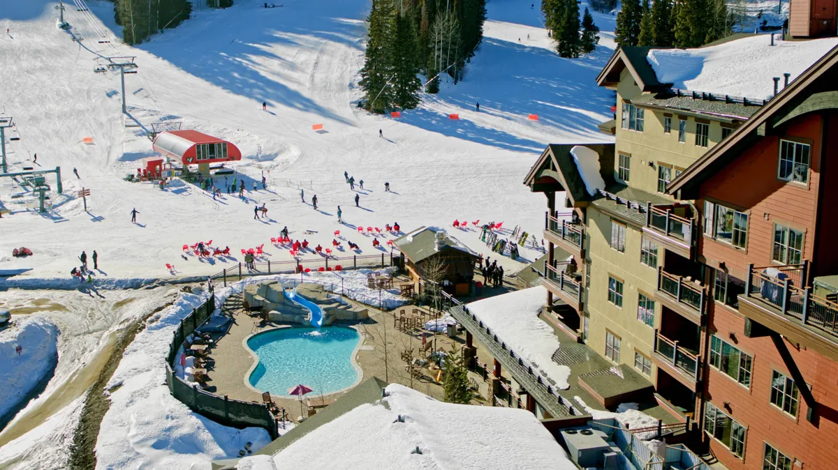 A lively exterior scene showcasing ski slopes bustling with skiers and snowboarders, a visible ski lift, a swimming pool surrounded by lounge chairs, and resort buildings nestled in the snow. The atmosphere is energetic and filled with winter activity, capturing both the excitement of the slopes and the appeal of après-ski socializing.
